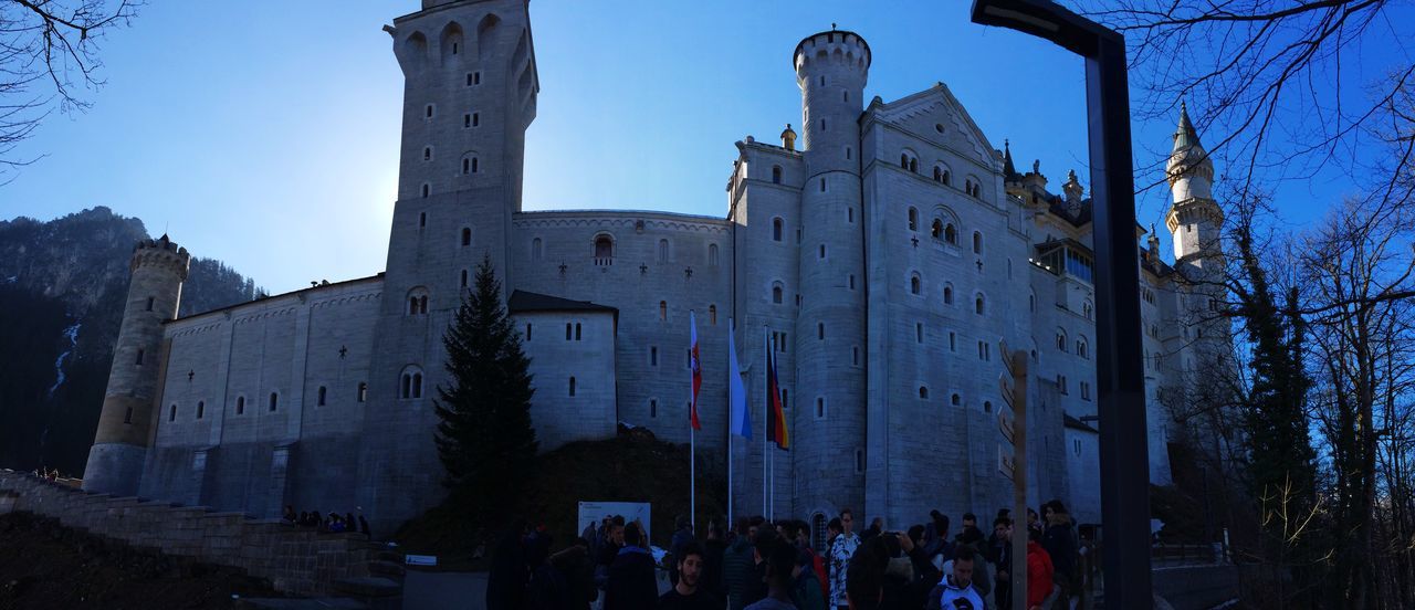 architecture, built structure, building exterior, clear sky, low angle view, blue, city, street, sky, history, sunlight, day, building, outdoors, men, shadow, person, large group of people, travel destinations