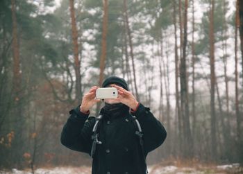 Man photographing through camera in forest