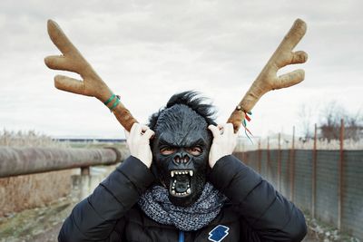 Close-up of man wearing gorilla mask against sky