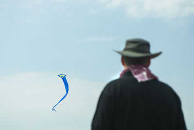 Rear view of man looking at kite against sky