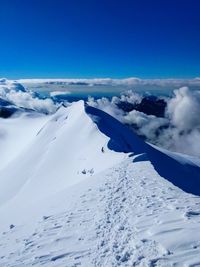 Scenic view of snow covered mountains against blue sky