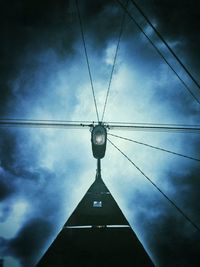 Low angle view of electricity pylon against cloudy sky