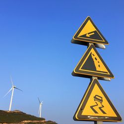 Low angle view of road signs against clear blue sky