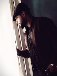 Young man looking away while standing at home