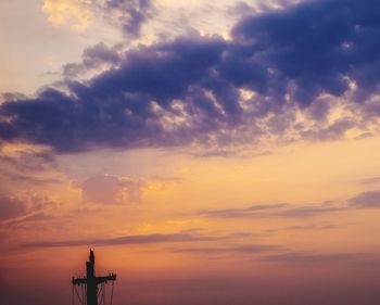 Silhouette of communications tower against sky during sunset