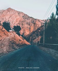 Road amidst trees and mountains against sky