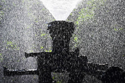 Blurred motion of man standing on wet fence during rainy season