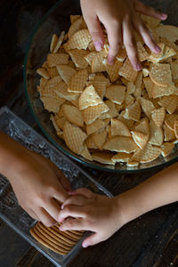 High angle view of hand crushing cookies in the bowl on table. top view.