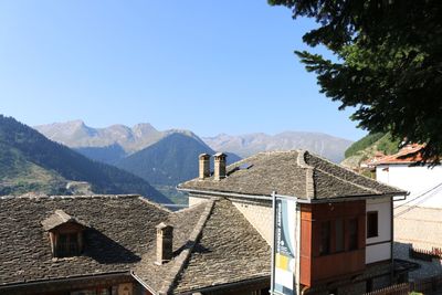 Houses by mountains against clear blue sky