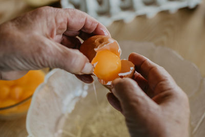 Older woman's hands with eggs preparing cakes and sweets
