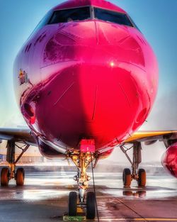 Close-up of airplane in airport runway against sky