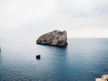 Rock formation in sea against sky