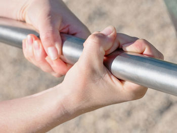 Hands grabbing steel monkey bars at a playground. holding on strong preventing falling, swinging