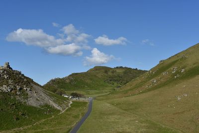 Scenic view of road by mountains against sky