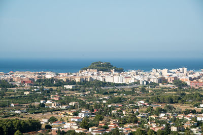 High angle view of cityscape by sea against clear sky