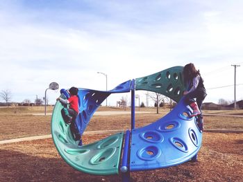 Rear view of boy on playground against sky