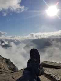 Low section of man standing on mountain against sky