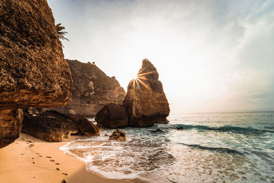 Rock formation at beach against sky