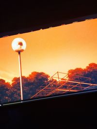 Low angle view of illuminated street light against orange sky