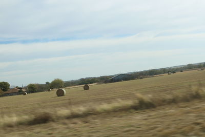 Hay bales on field against sky