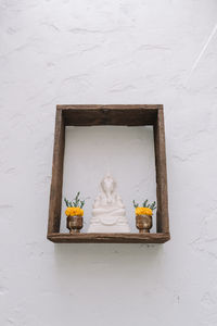 Close-up of buddha statue against white wall