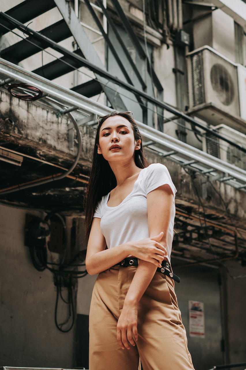 one person, young women, young adult, three quarter length, real people, architecture, lifestyles, standing, casual clothing, built structure, front view, hair, building exterior, hairstyle, women, leisure activity, focus on foreground, looking, beautiful woman, contemplation