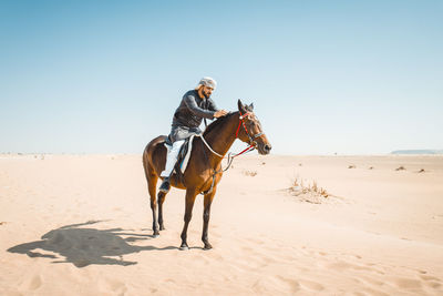 Man riding horse on sand