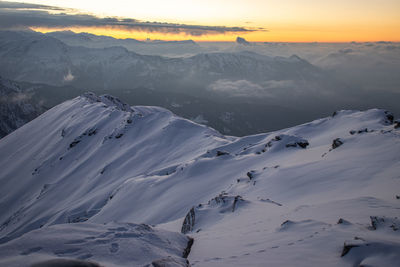 Scenic view of snow covered mountains against sky during sunset