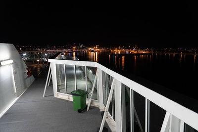 Illuminated bridge over river by buildings in city at night