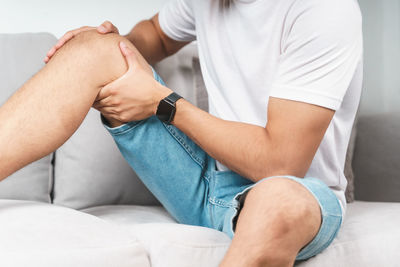 Midsection of man sitting on sofa at home