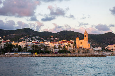 Buildings by river against sky
