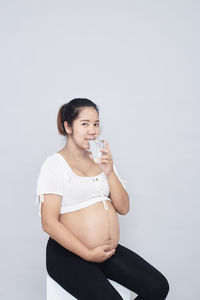 Young woman looking away while standing against white background