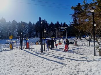 People on snow covered field against sky