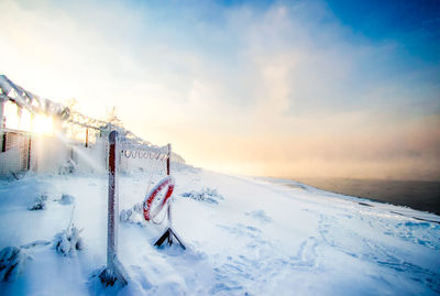 Life belt hanging on snow covered mountain against sky