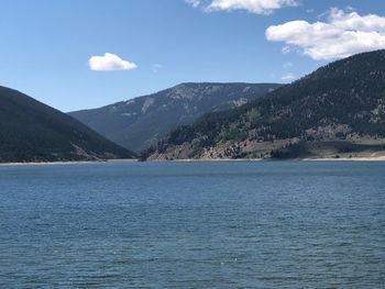 Scenic view of sea by mountains against sky