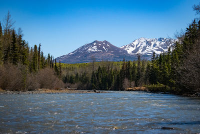 Scenic view of lake by mountains against clear blue sky