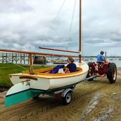 Boats in river against cloudy sky