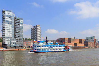 Nautical vessel on sea by buildings against sky