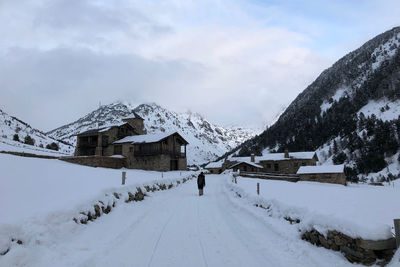 Snow covered houses by mountain against sky