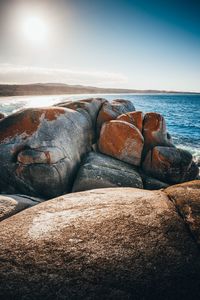 Rocks on shore at beach against sky