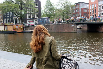 Rear view of woman with umbrella in canal