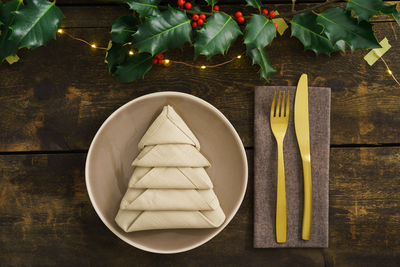 High angle view of napkin in plate by cutleries arranged on wooden table