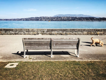 View of an empty bench by sea against sky