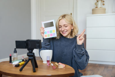 Young woman using mobile phone while sitting on table