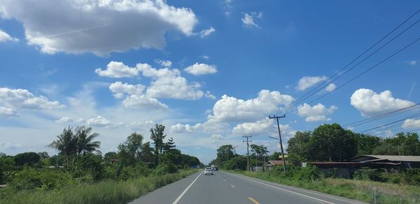 Road by trees against sky