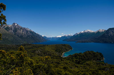 Scenic view of lake and mountains against clear blue sky