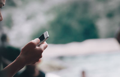 Close-up of hand holding mobile phone outdoors