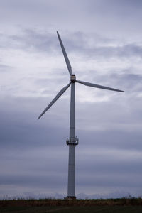 Low angle view of windmill on field against sky