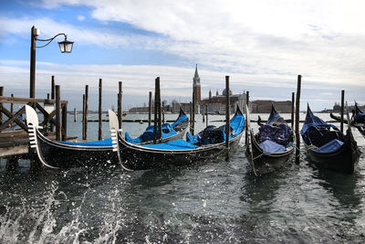 Gondolas moored at harbor with church of san giorgio maggiore in background