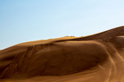 Sand dunes in desert against clear sky